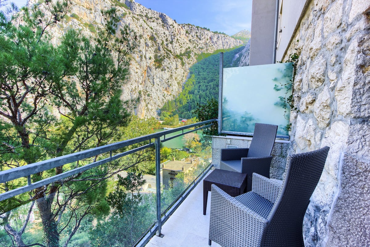 Un balcón con mobiliario de mimbre que da a un paisaje montañoso.