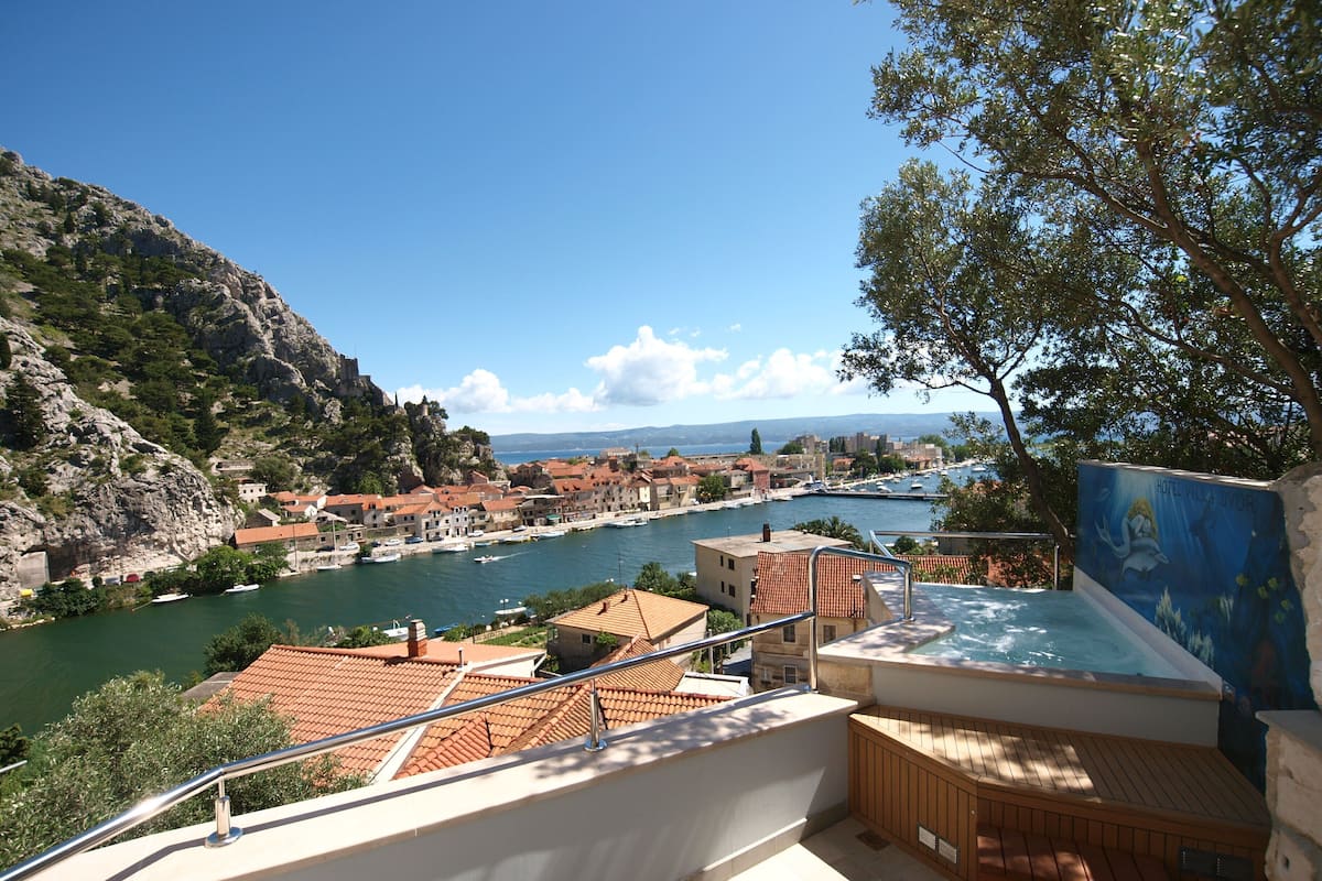 Un pueblo costero con vista al mar, una piscina y una terraza con mobiliario de madera.