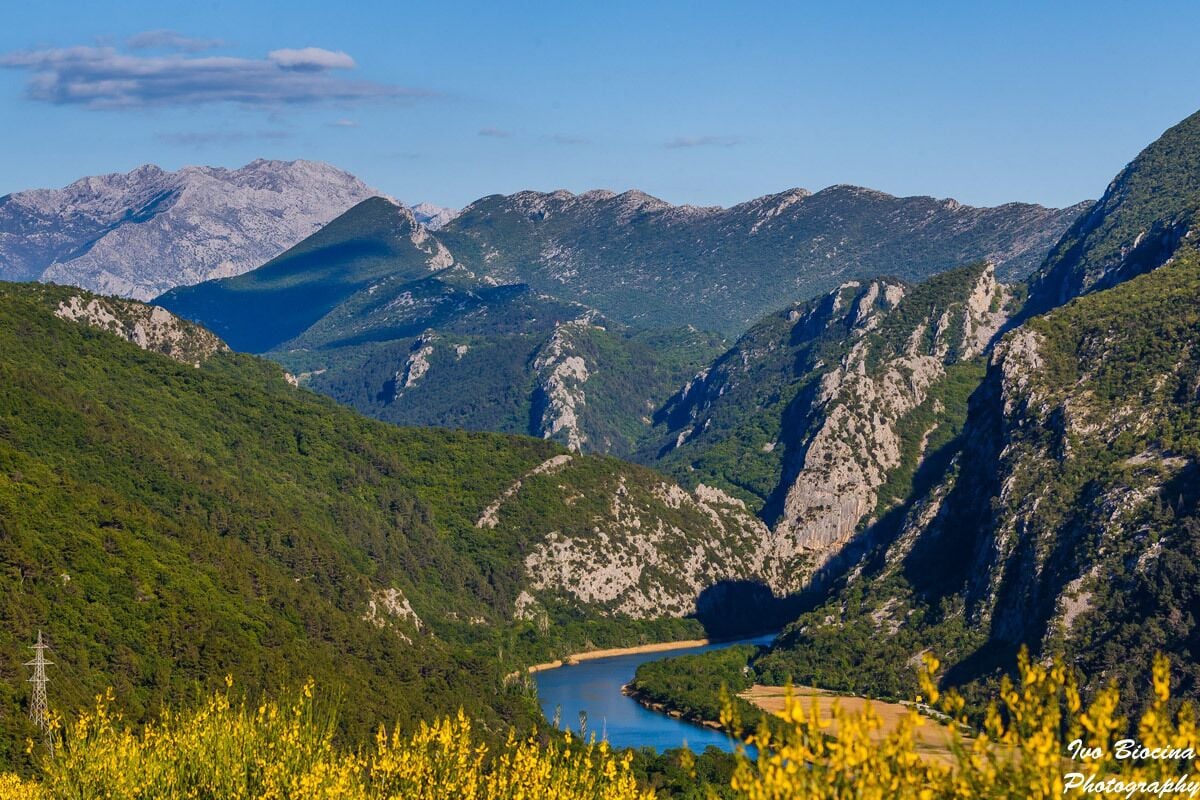 Un paisaje montañoso con un río, vegetación densa y montañas al lejano.