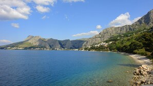 Un paisaje costero con aguas azul turquesa, costas rocosas y terreno montañoso al fondo.