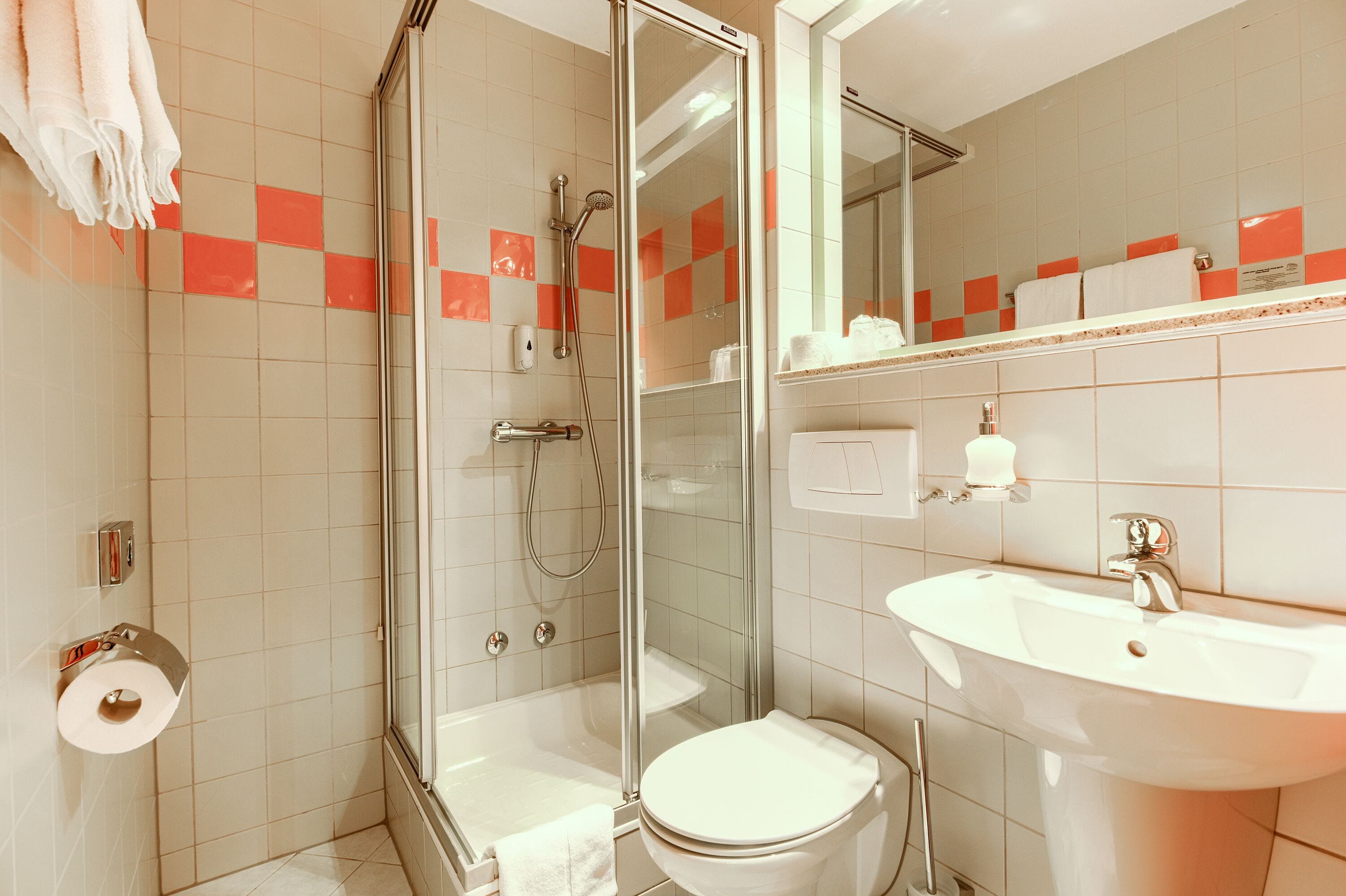 A bathroom with a glass-enclosed shower, a white sink, and a toilet.