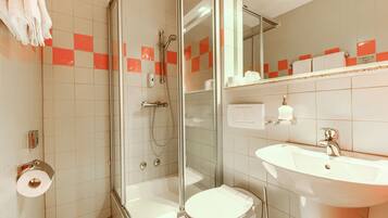 A bathroom with a glass-enclosed shower, a white sink, and a toilet.