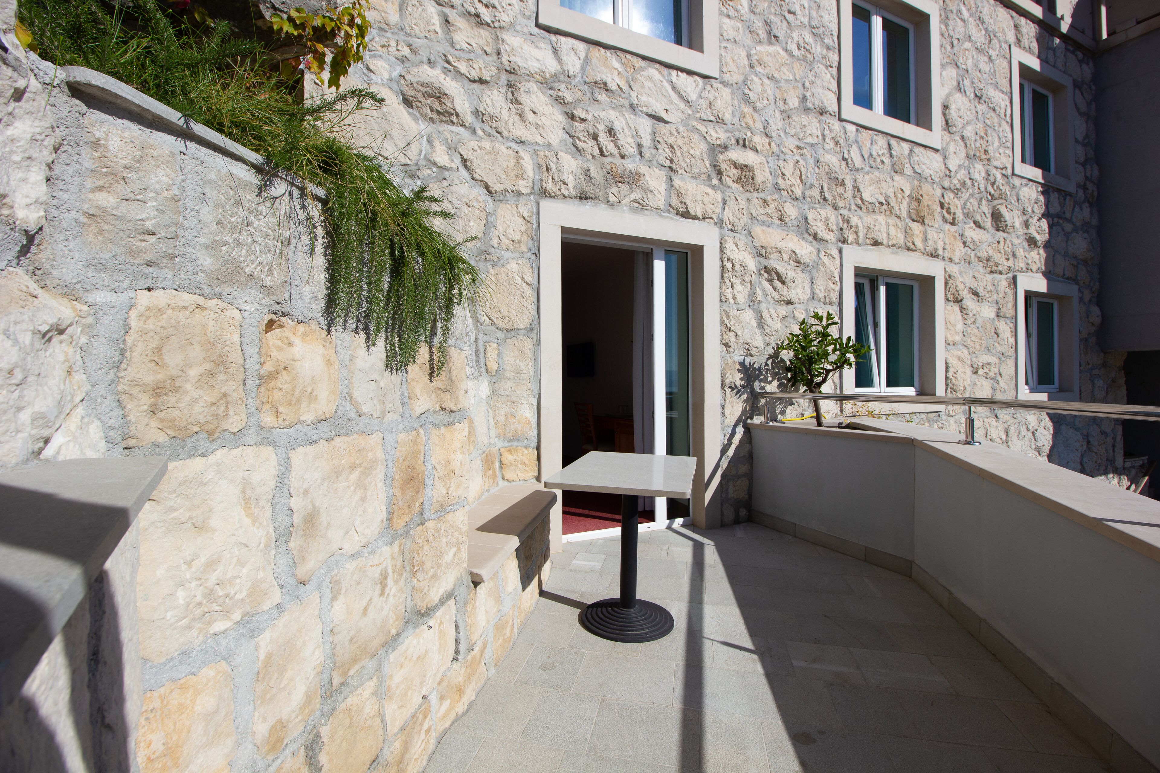 A stone building with a balcony, a table, and a chair.