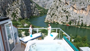 Un jacuzzi en un balcón con vistas a un río y montañas.