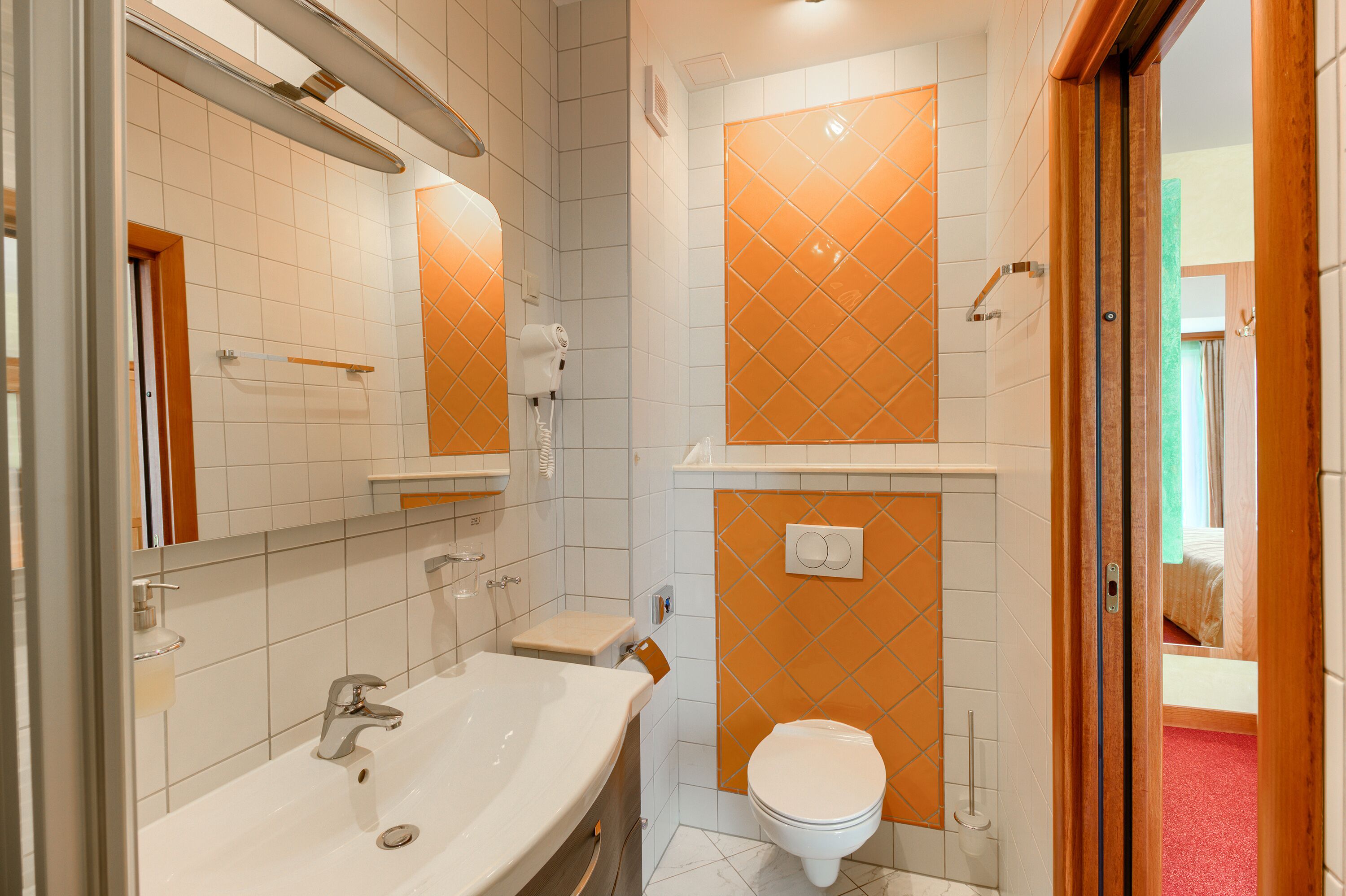 Un baño con lavamanos, espejo y retrete.