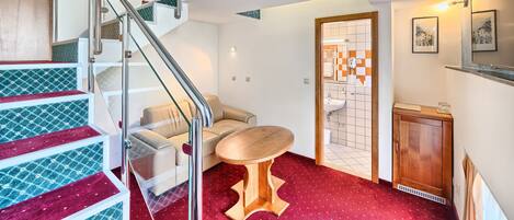 A modern interior with a staircase, a sofa, a small table, and a cabinet.