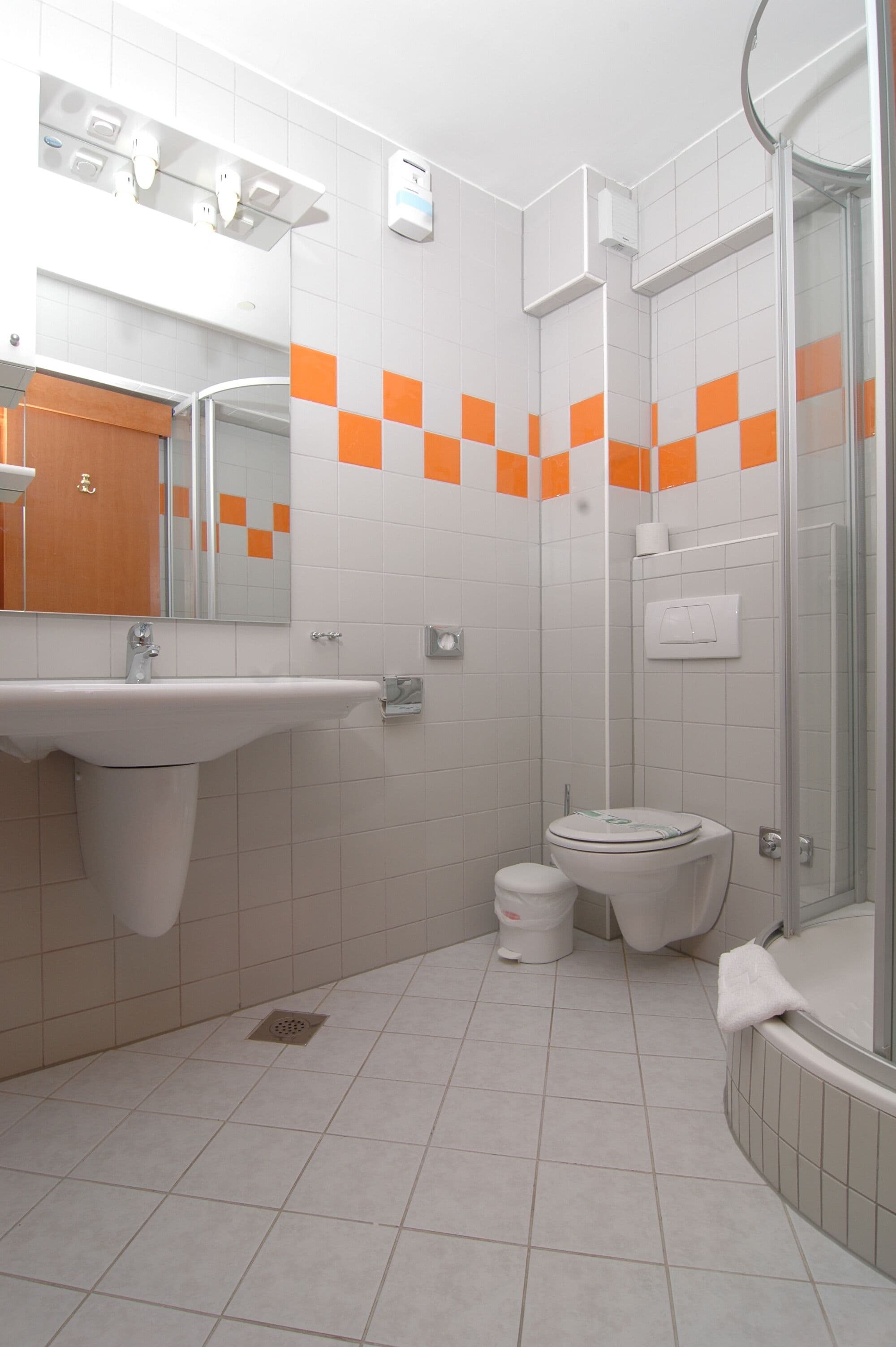Un baño moderno con un lavamanos blanco, un inodoro y una cabina de ducha con paredes de vidrio.