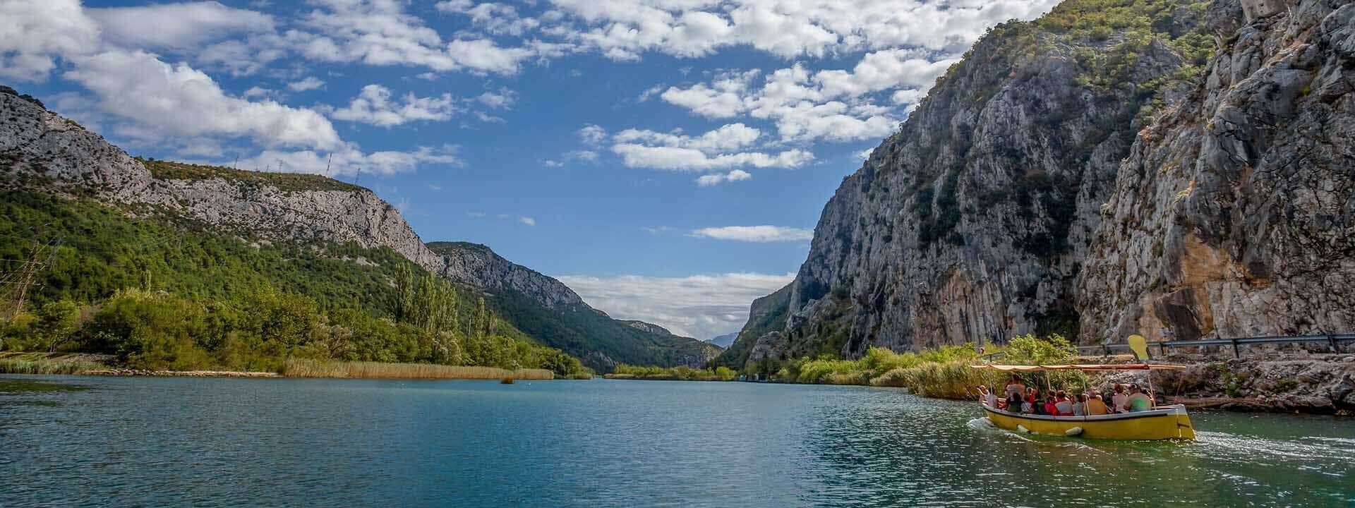 Un bateau sur une rivière, entouré de falaises rocheuses et de verdure.