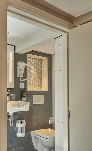 A modern bathroom with a toilet, sink, and a shower area. - ITC Hotel (Amsterdam)