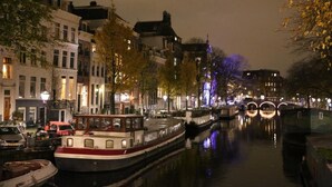A nighttime canal scene with boats, buildings, and a bridge. - ITC Hotel (Amsterdam)