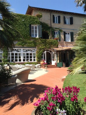 A villa with a patio, outdoor furniture, and a garden.