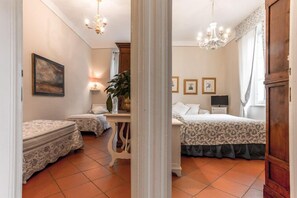 A bedroom with two beds, a nightstand, a lamp, and a painting on the wall.