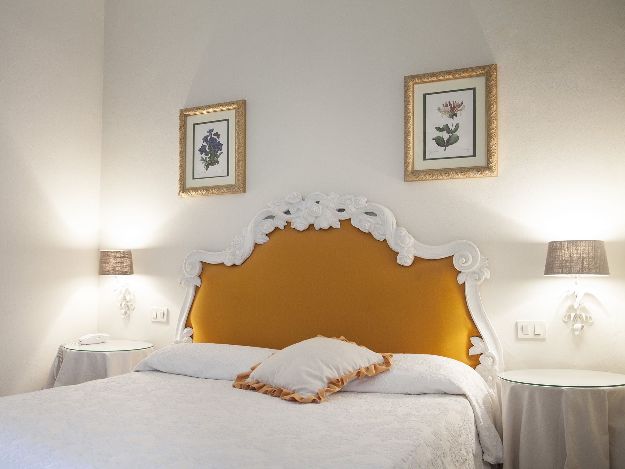 A neatly arranged bedroom with a large bed, two bedside tables, and two wall-mounted lamps.