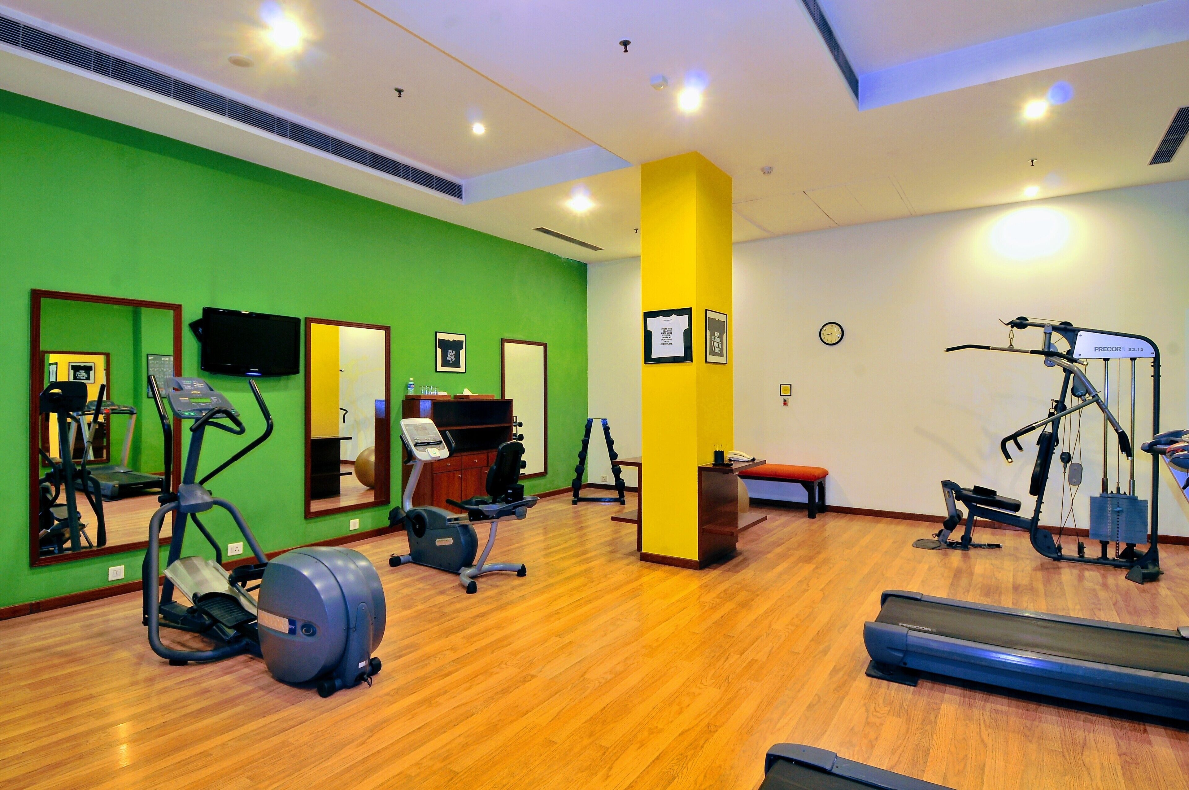 Una palestra con diverse attrezzature per esercizi, specchi e un pavimento in legno.