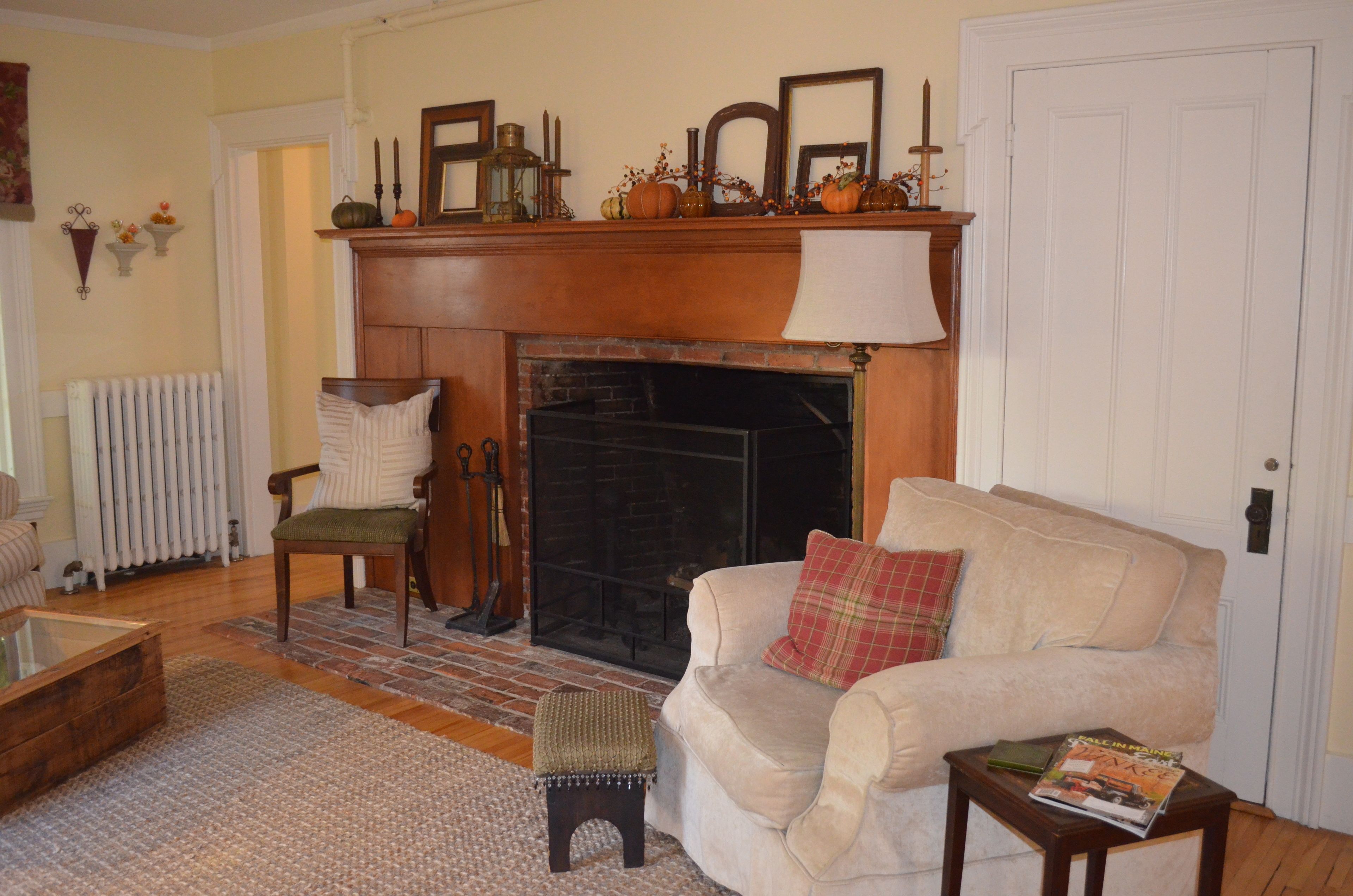 A cozy living room with a fireplace, a comfortable sofa, a small table, and a radiator.