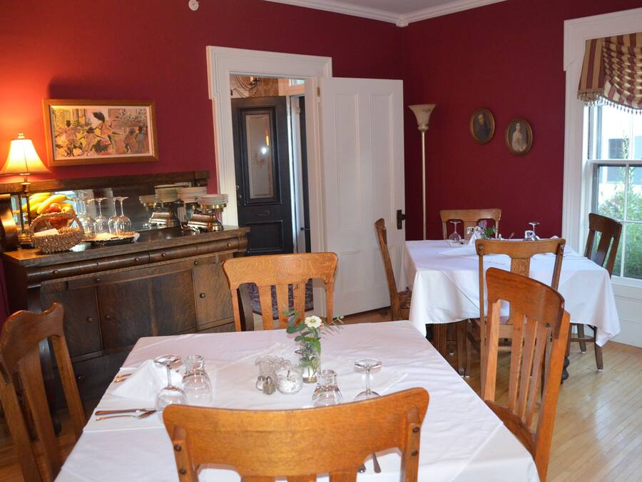 A dining area with wooden chairs and tables, a buffet counter, and a door leading to another room.