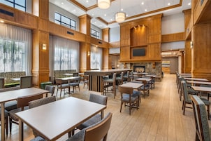 A spacious dining area with wooden paneling, multiple tables and chairs, and a central bar area.