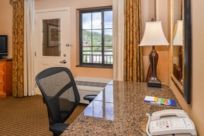 Enjoy a peaceful retreat with a forest view from this cozy room, featuring a desk, chair, and TV.