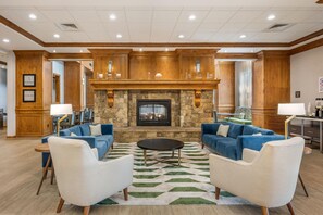 A spacious lobby with a stone fireplace, blue sofas, and a round coffee table. - Hampton Inn & Suites Coeur d' Alene (Coeur d'Alene)