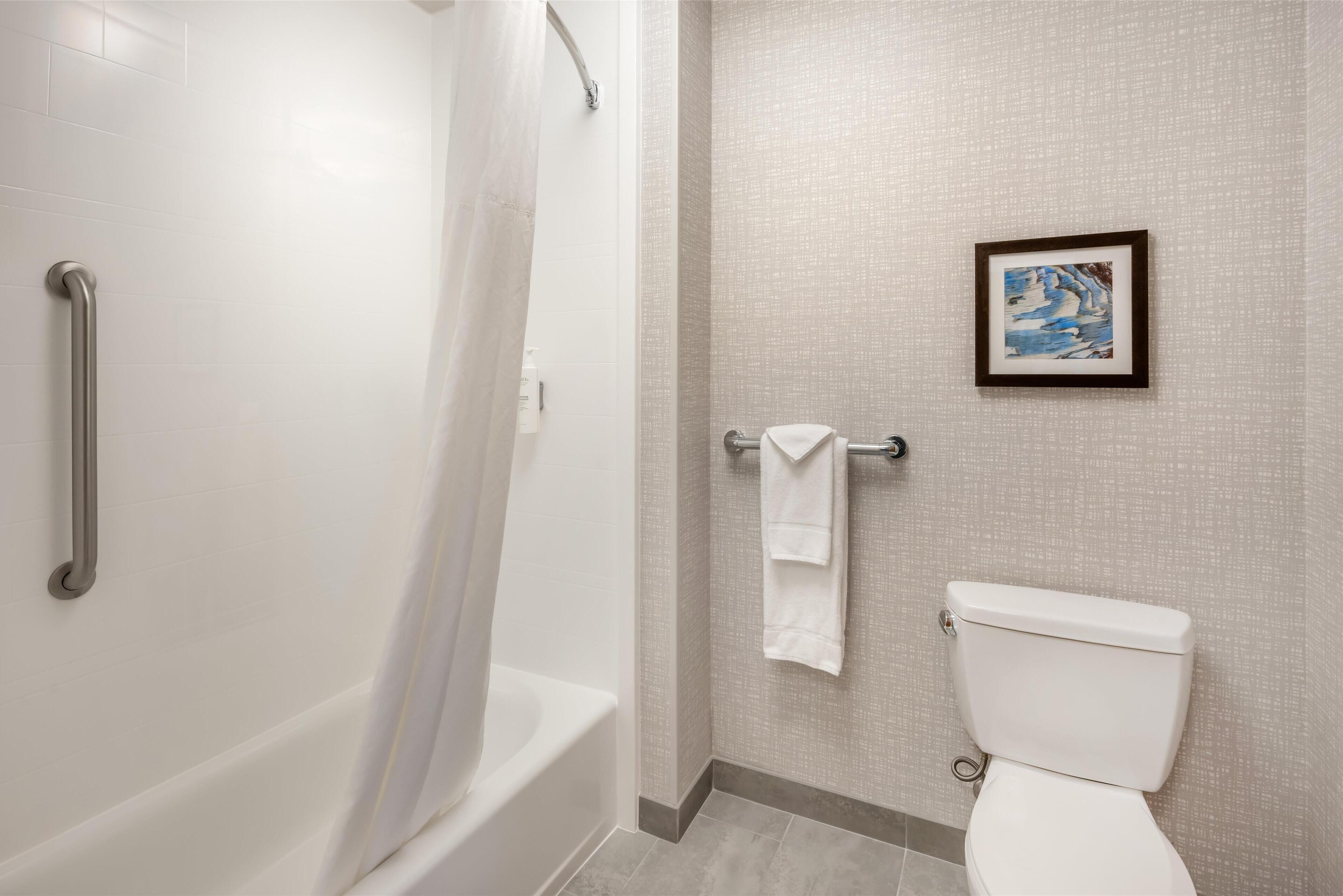 A bathroom with a shower, a toilet, and a towel rack.