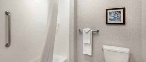 A bathroom with a bathtub, toilet, and a towel rack.