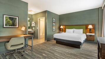 A hotel room with a bed, desk, chair, and two bedside lamps.