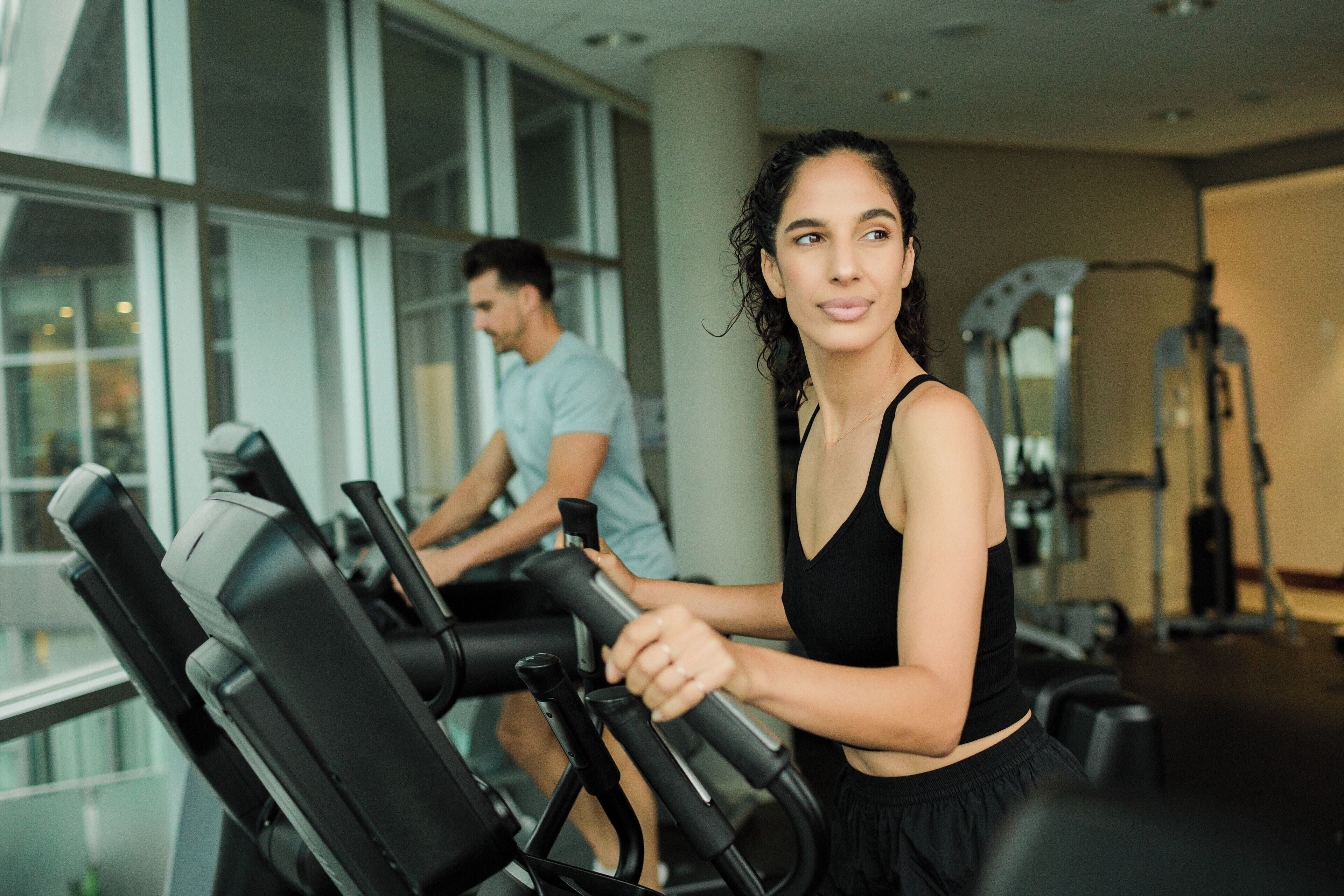 A gym with exercise equipment and large windows.