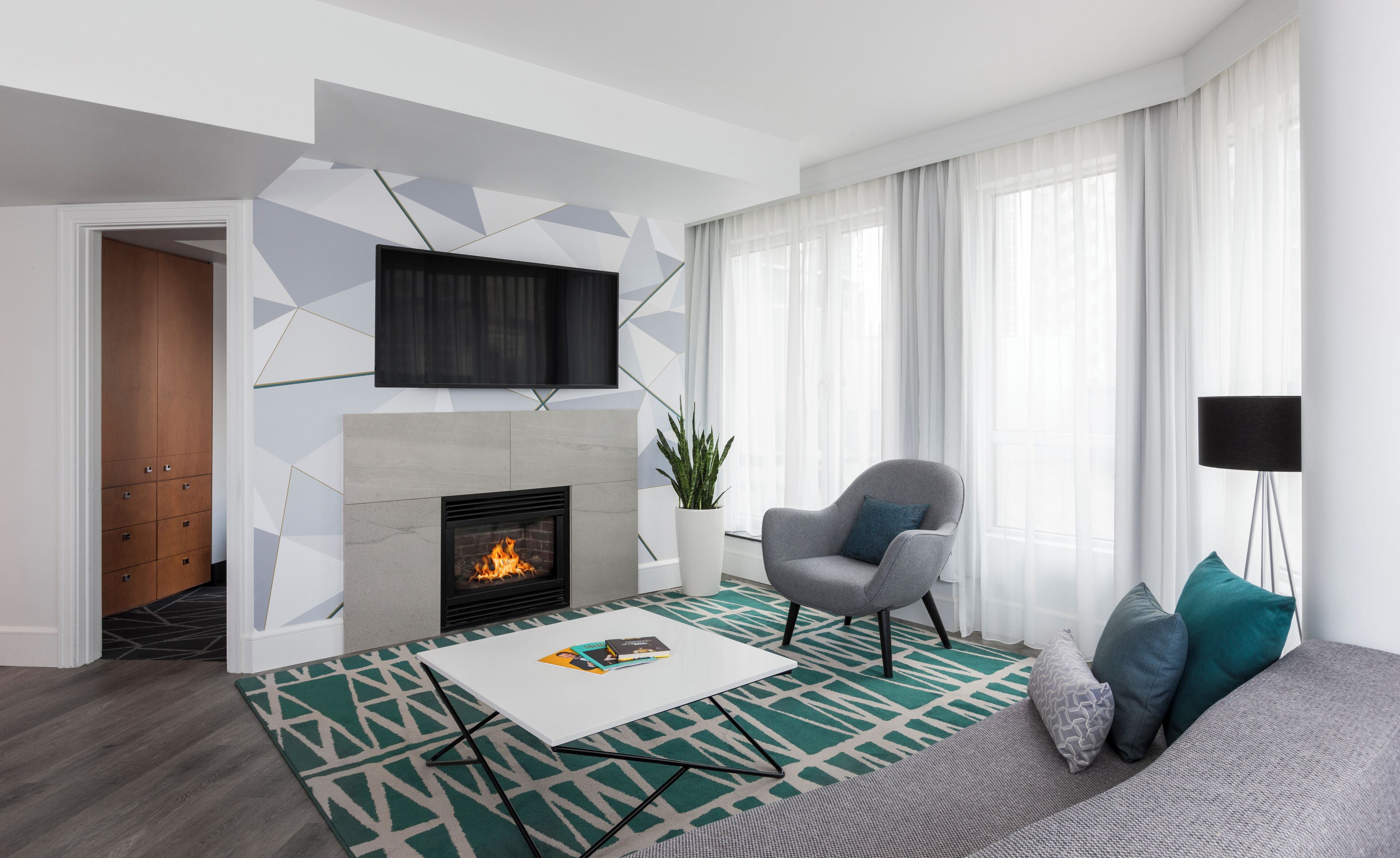 A modern living room with a fireplace, a sofa, a coffee table, and a TV mounted on the wall.