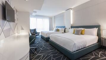 A hotel room with two beds, a desk, a chair, and a TV mounted on the wall.