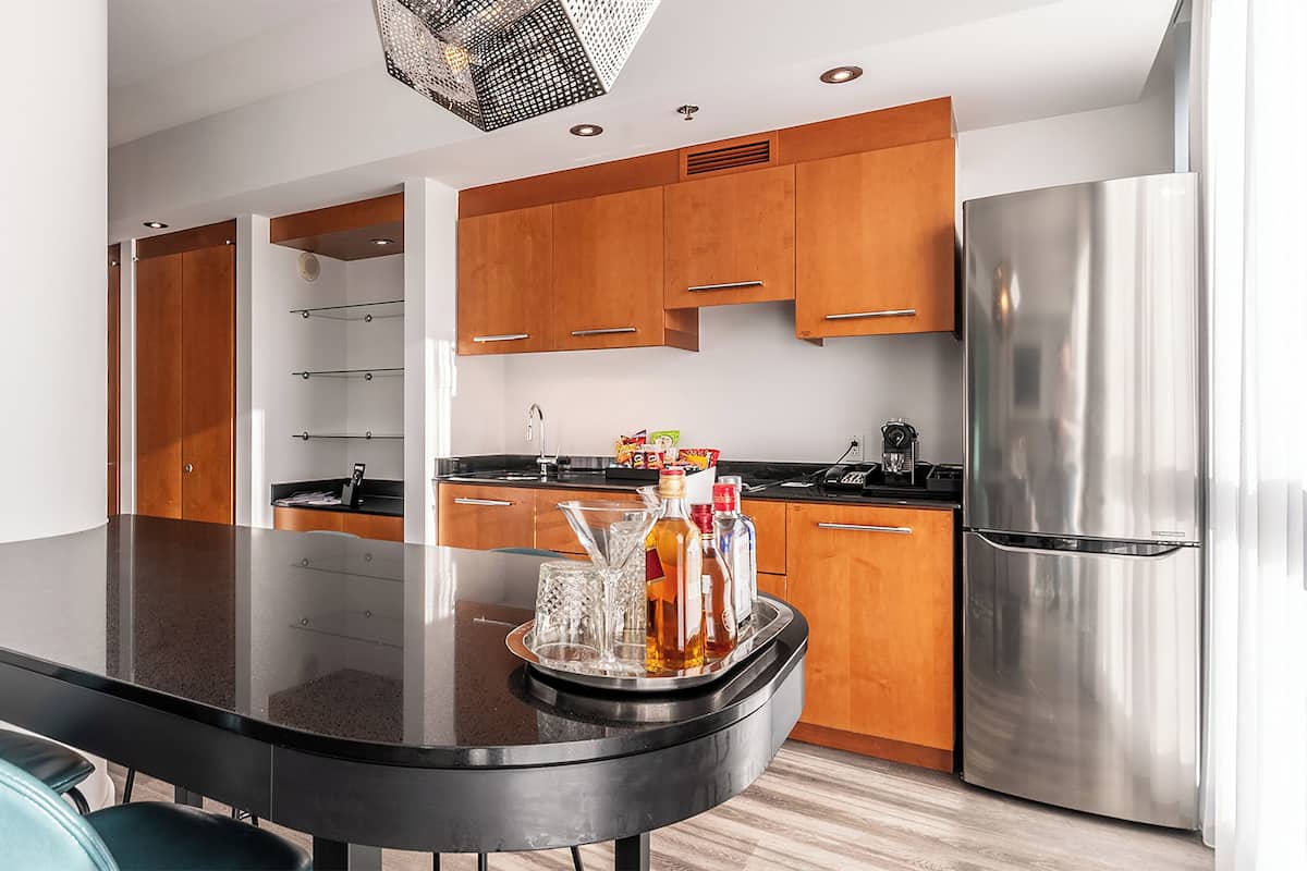 Una cocina moderna con armarios de madera, un refrigerador de acero inoxidable y una mesa de comedor de vidrio con sillas.