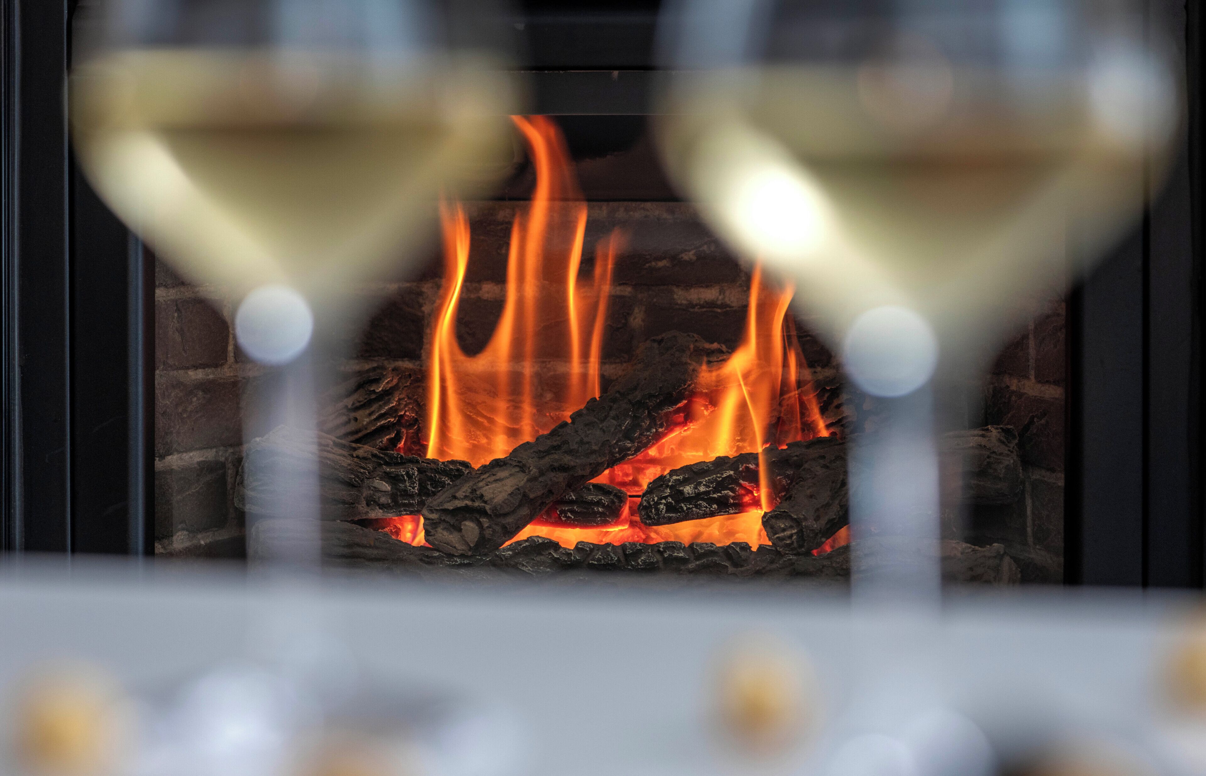 A fireplace with burning logs and a glass barrier.