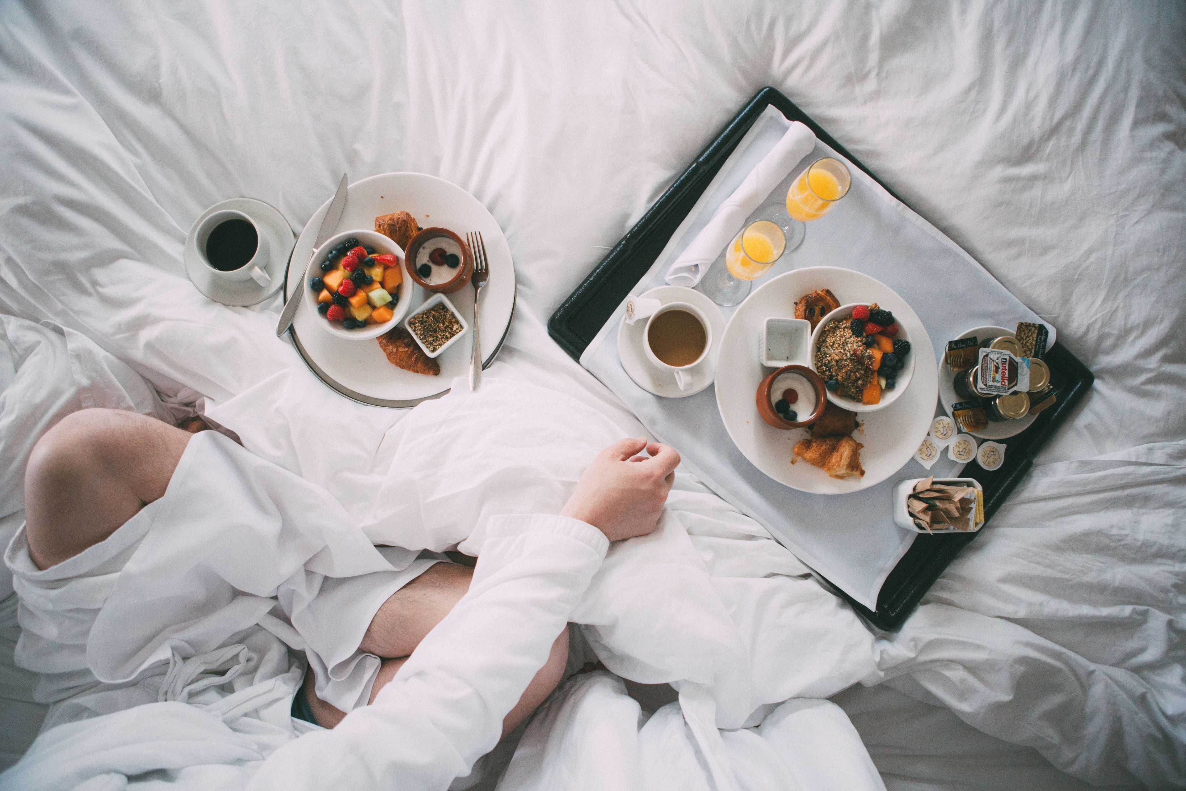 A bed with a tray containing breakfast items, including toast, fruit, and coffee.