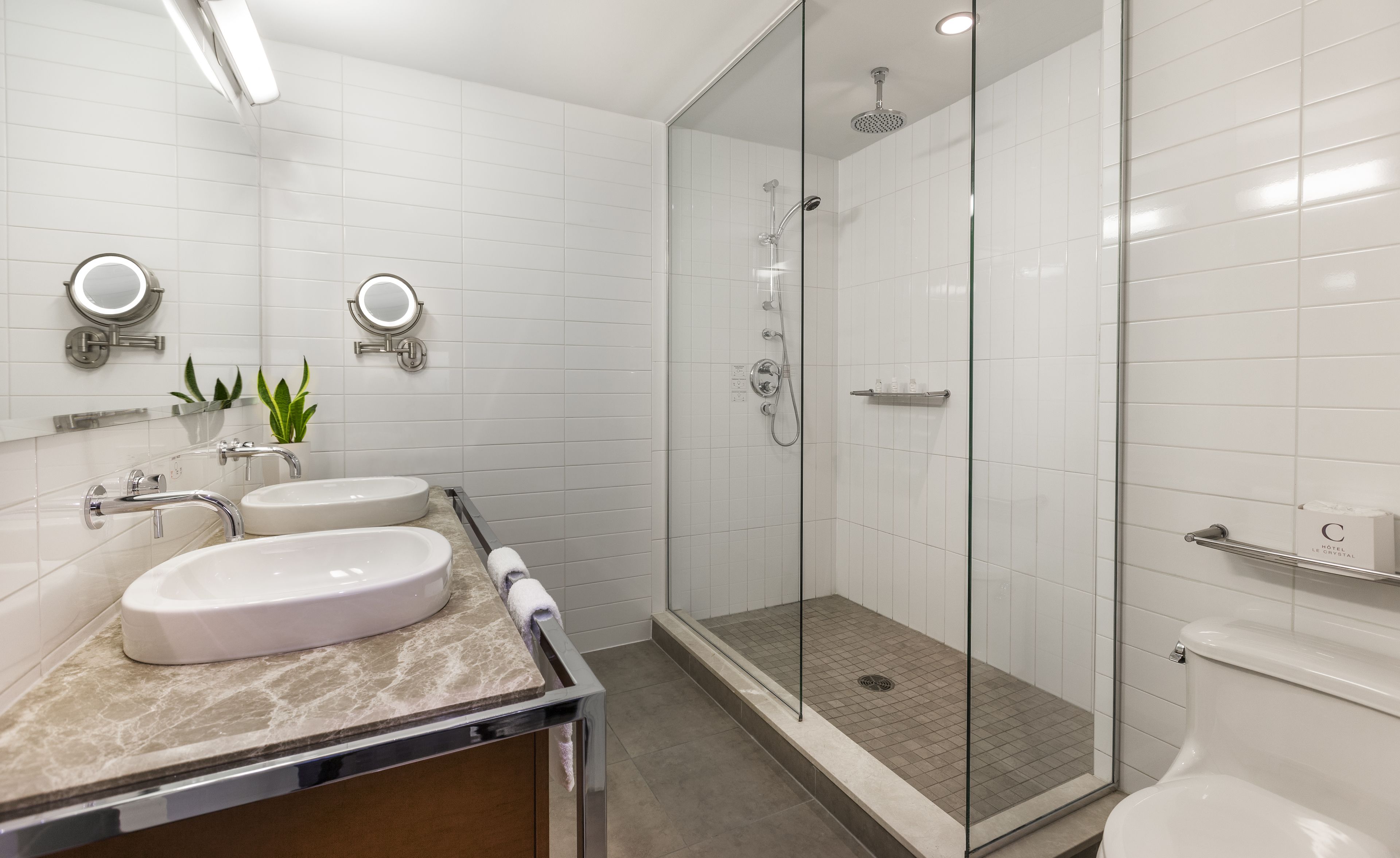 Un baño moderno con dos lavamanos, cabina de ducha de vidrio y un inodoro.