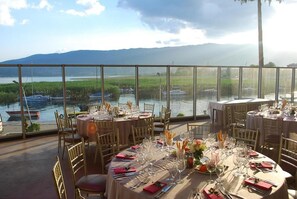 A restaurant with tables set for dining, overlooking a body of water with boats and greenery. - Hotel Drim (Struga)