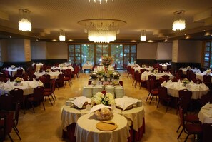 A banquet hall with round tables, chandeliers, and a central floral arrangement. - Hotel Drim (Struga)