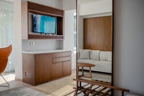 A modern living room with a wooden cabinet, a flat-screen TV, a white sofa, and a small wooden table. - Hotel Drim (Struga)