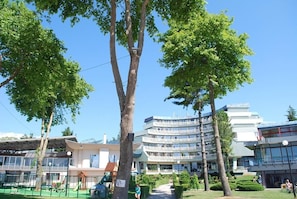 A multi-story building with a modern architectural style, surrounded by greenery and trees. - Hotel Drim (Struga)