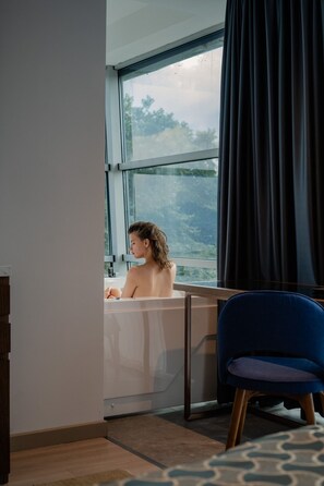 A room with a large window, a bathtub, and a blue chair. - Hotel Drim (Struga)