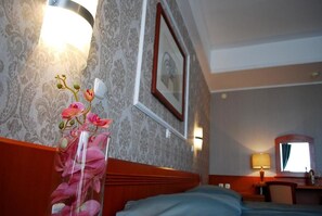 A hotel room with a bed, a nightstand, a lamp, a mirror, and a framed picture on the wall. - Hotel Drim (Struga)