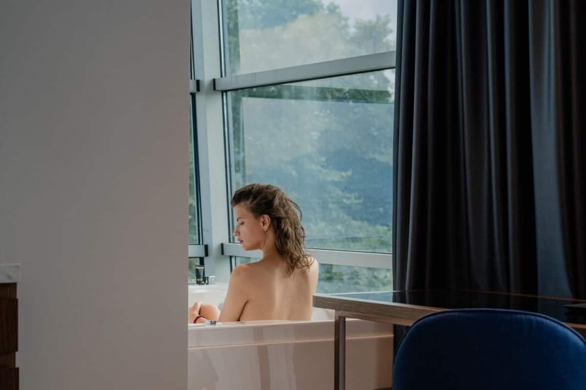 A room with a large window, a bathtub, and a blue chair.