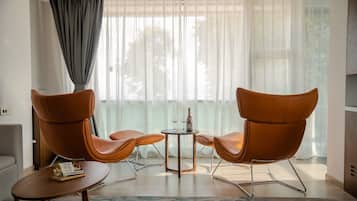 A modern living room with two leather armchairs, a small round table, and a bookshelf.