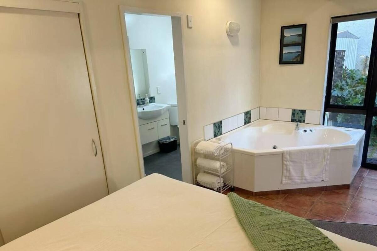 A bedroom with a large bed, a bathroom with a bathtub, and a view of the outdoors.