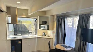 Una cocina compacta con fregadero, microondas y un pequeño comedor con mesa y sillas.