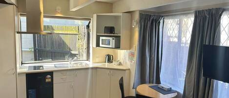 Una cocina compacta con fregadero, microondas y un pequeño comedor con mesa y sillas.