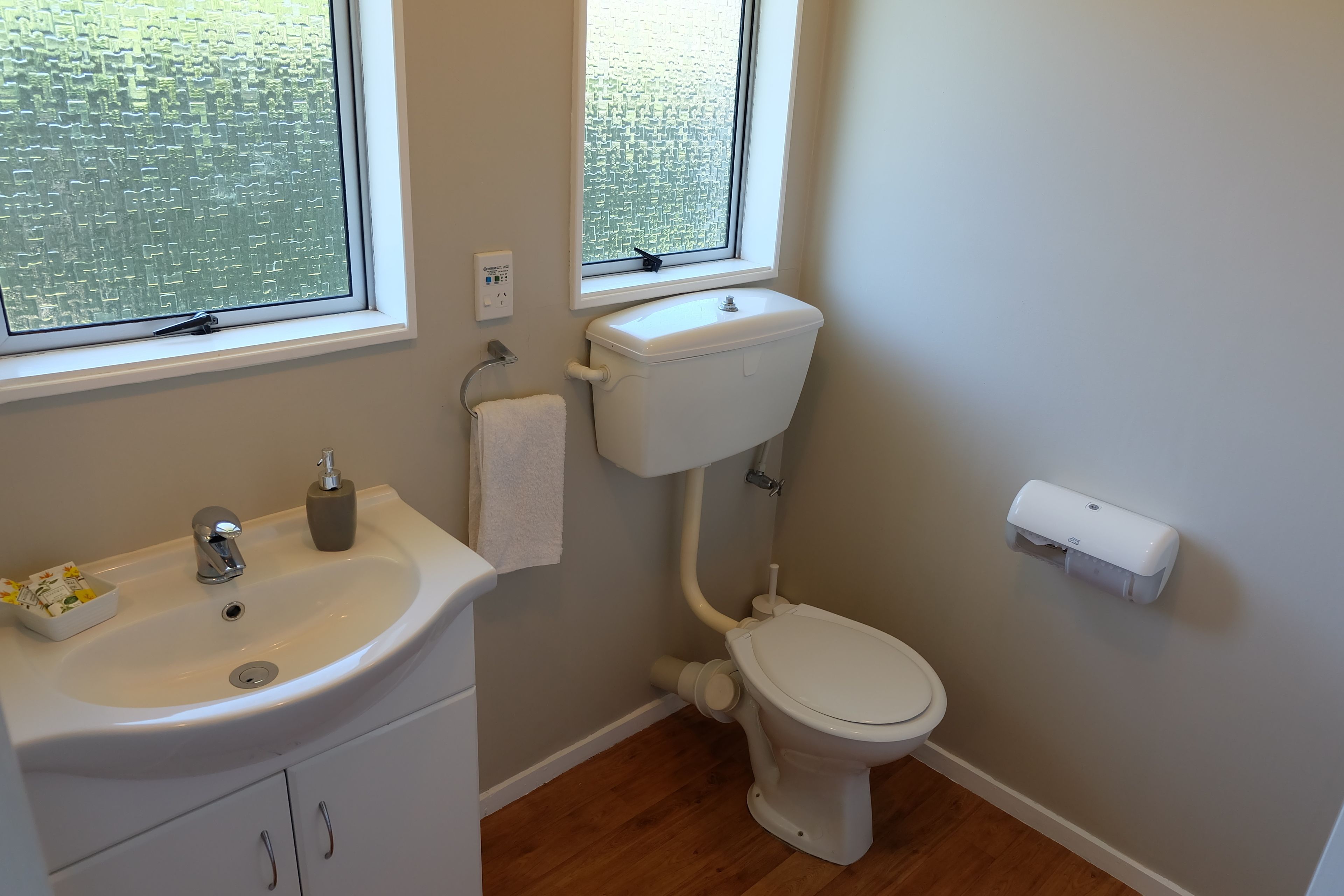A bathroom with a toilet, sink, and window.