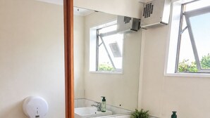 A bathroom with two sinks, a toilet, a towel rack, and a window.