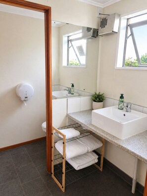 A bathroom with two sinks, a toilet, a towel rack, and a window.