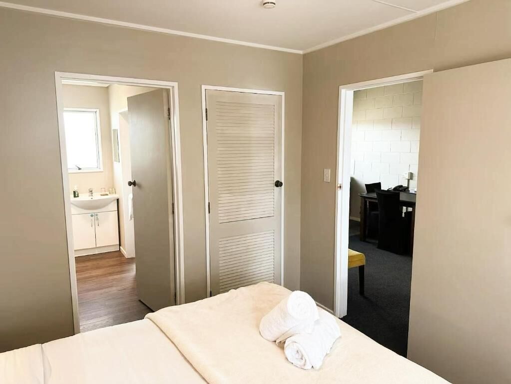 Une chambre d’hôtel avec un lit, une salle de bain avec un lavabo et un bureau.