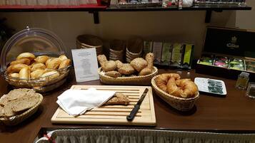 Buffet de café da manhã com pães, doces e opções de chá variados.