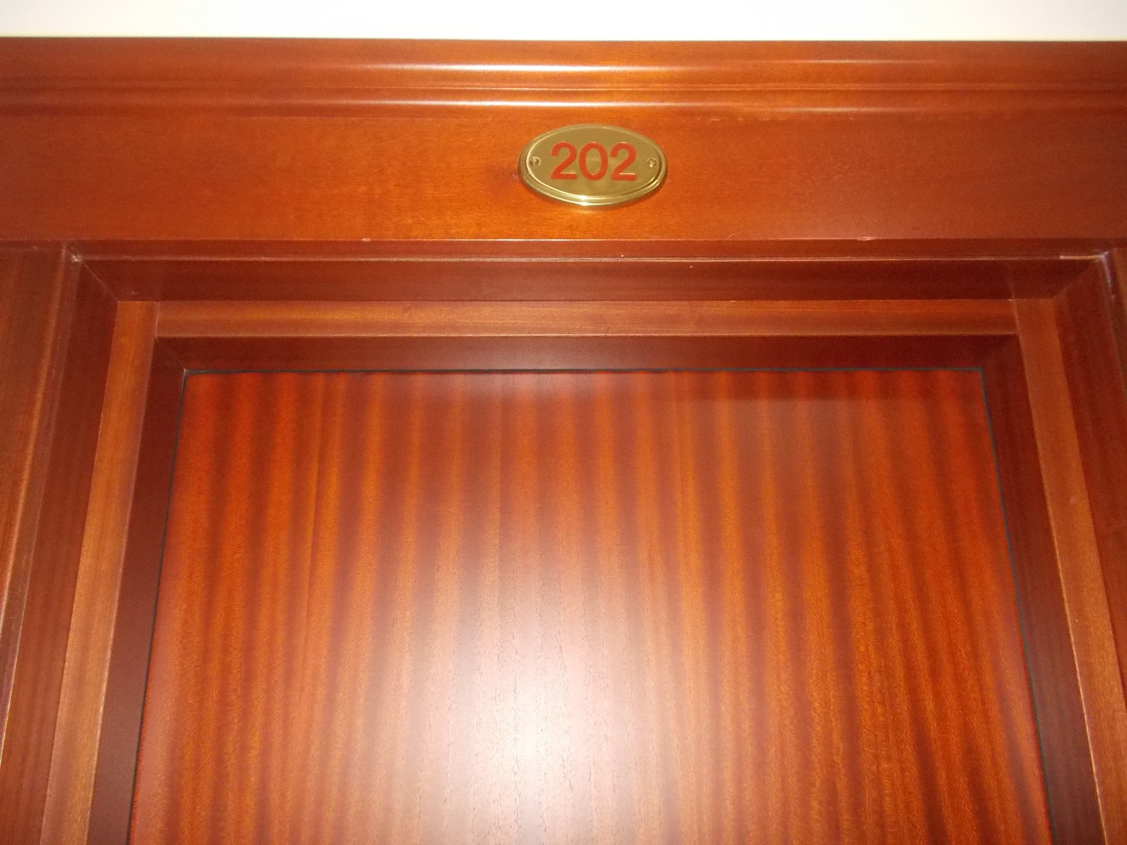 A wooden door with a brass plaque reading "202".